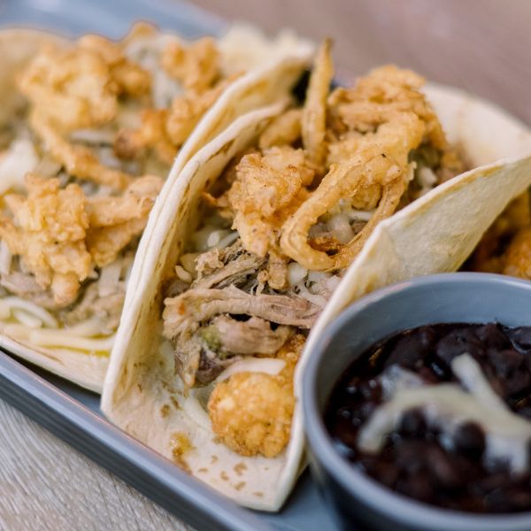 Soft tacos with shredded meat, cheese, crispy fried onions, and black beans.