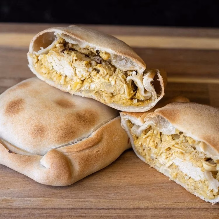 Baked pastries with shredded chicken filling, one whole, two cut open.