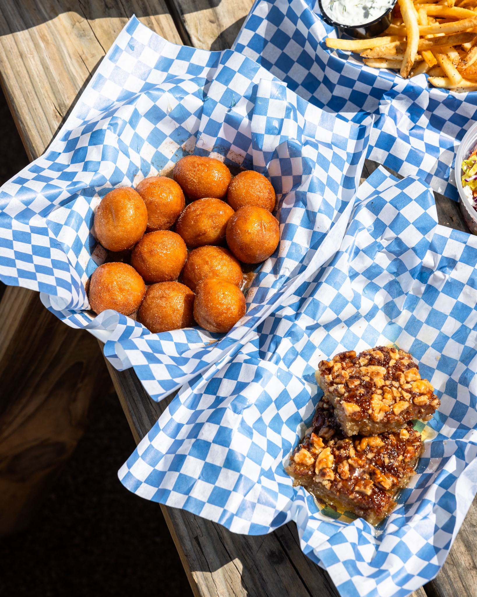 Fried dough balls and nut pastries on an outdoor wooden table.