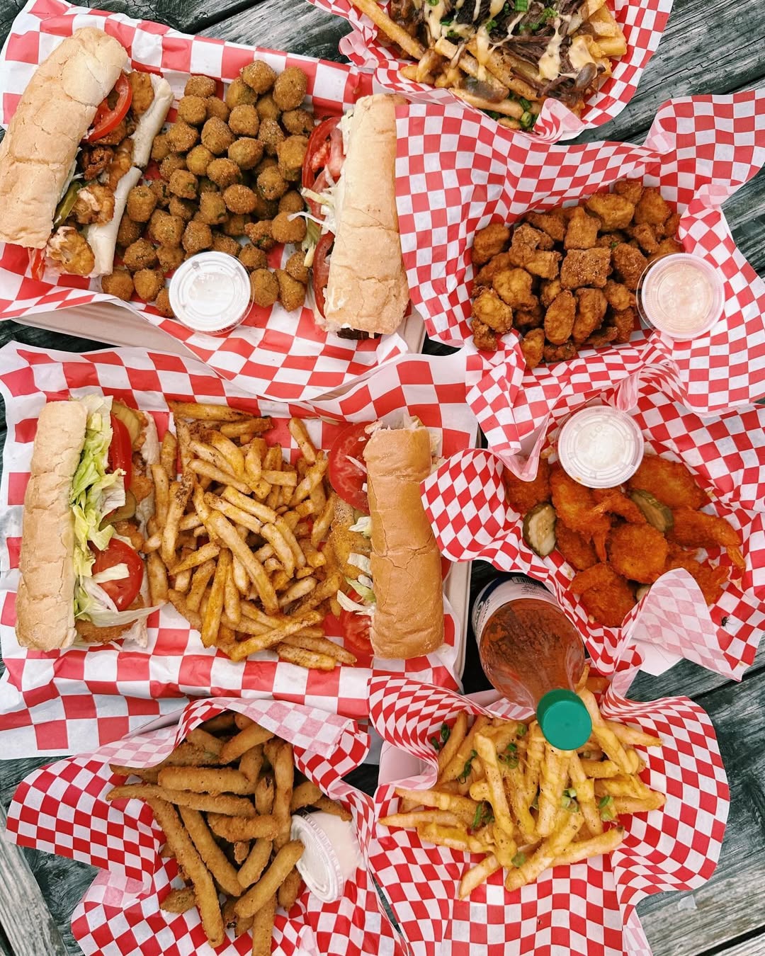 Multiple baskets of fried food, including po'boys, fries, and okra.