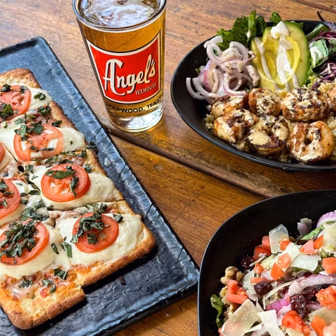 An Angel's Icehouse beer, flatbread pizza, grilled shrimp, and salads.
