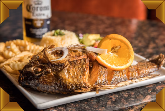 Whole fried fish, rice, french fries, and orange slices.