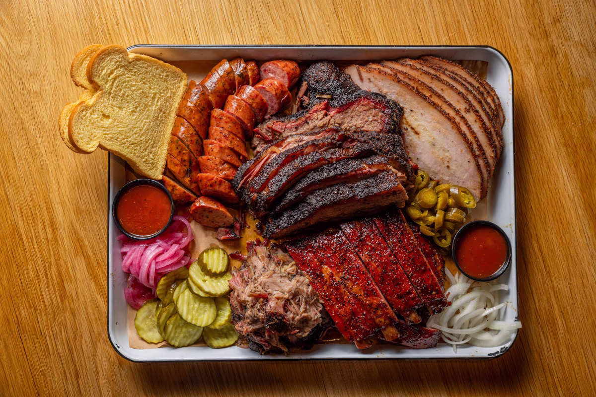 Platter of smoked meats: brisket, ribs, sausage, pulled pork, and sides.