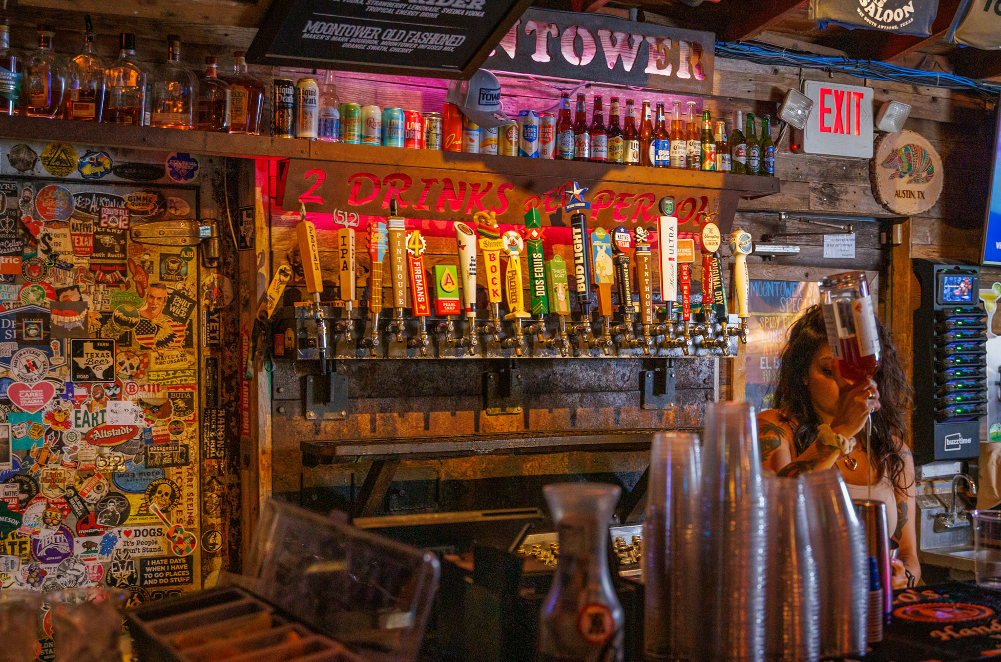 Bartender pouring a drink at a busy bar with many beer taps.