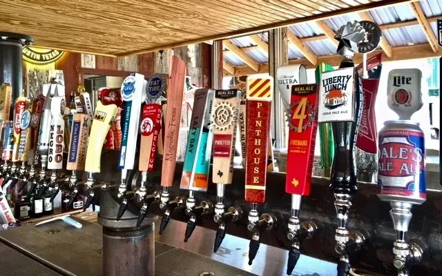 Close-up of numerous distinct beer tap handles against wood.