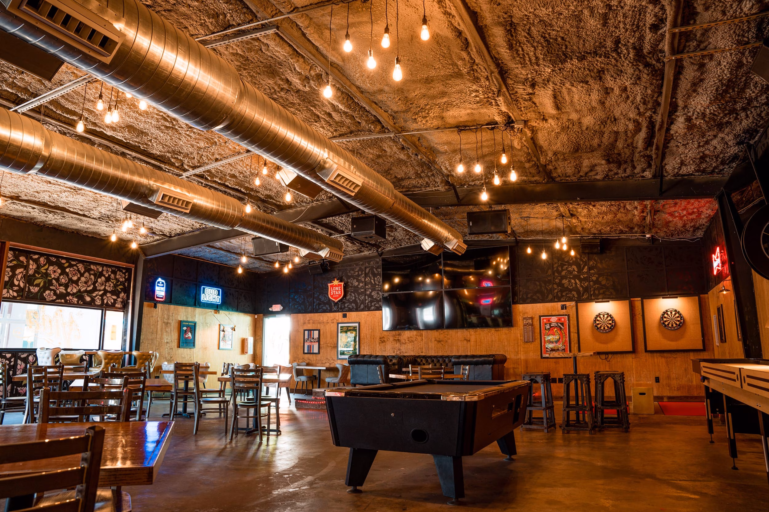 Interior of a casual bar with pool table, dartboards, and exposed ductwork.