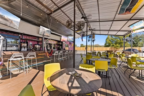 Outdoor bar patio with lime green chairs and shipping container bar.
