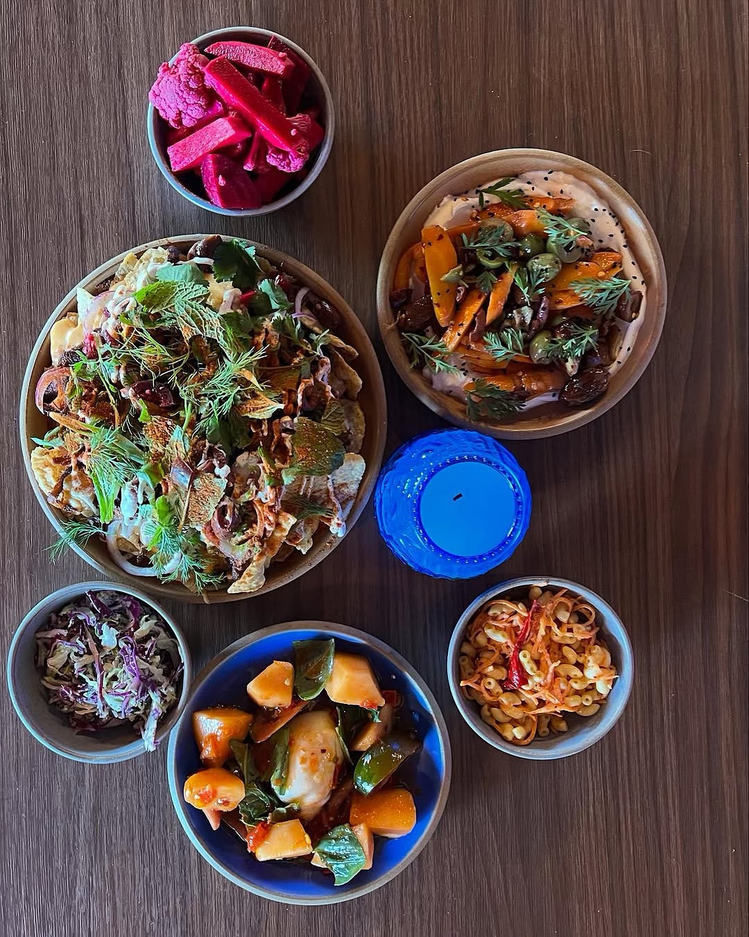 Overhead shot of colorful food bowls and a blue candle on a table.