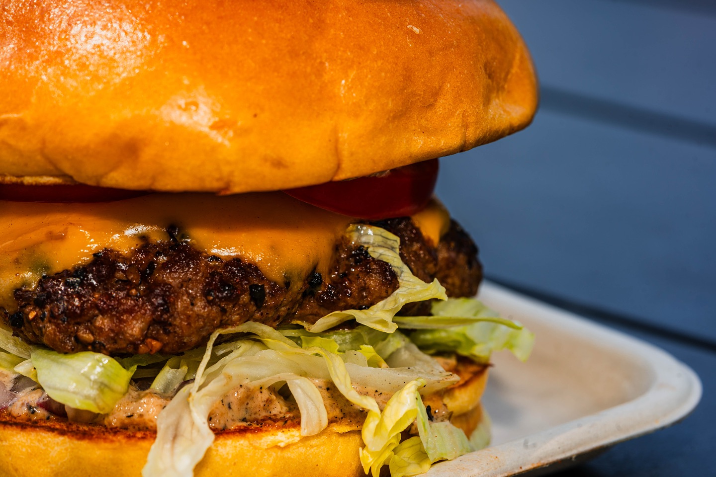 Double cheeseburger with melted cheese, lettuce, tomato, and sauce.