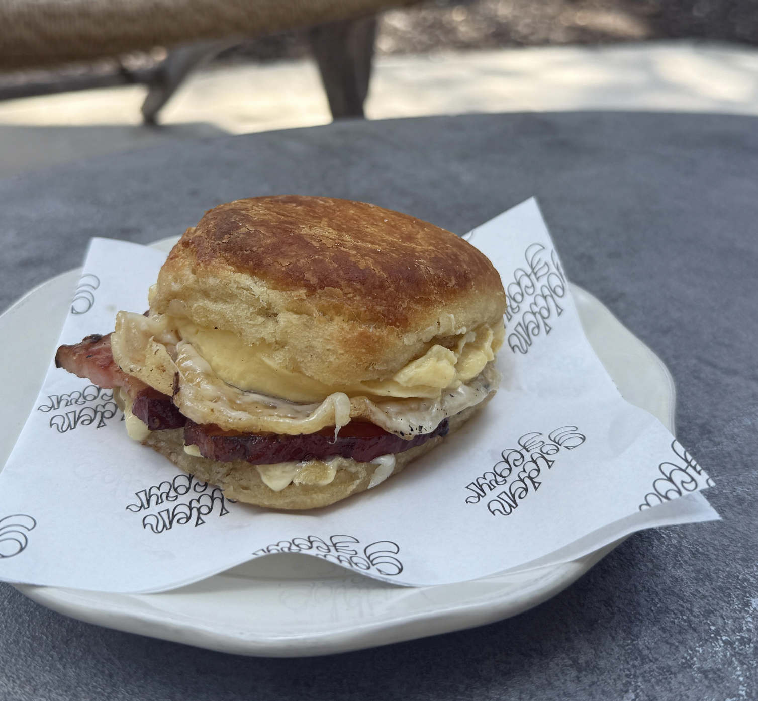 Biscuit sandwich with scrambled egg, melted cheese, and ham.
