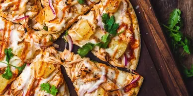 Hawaiian barbecue chicken pizza on a wooden board.