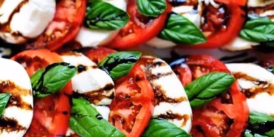Rows of Caprese salad with tomato, mozzarella, basil, and balsamic glaze.