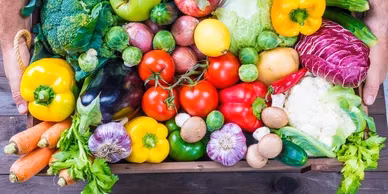 Close-up of a wooden crate overflowing with diverse fresh produce.