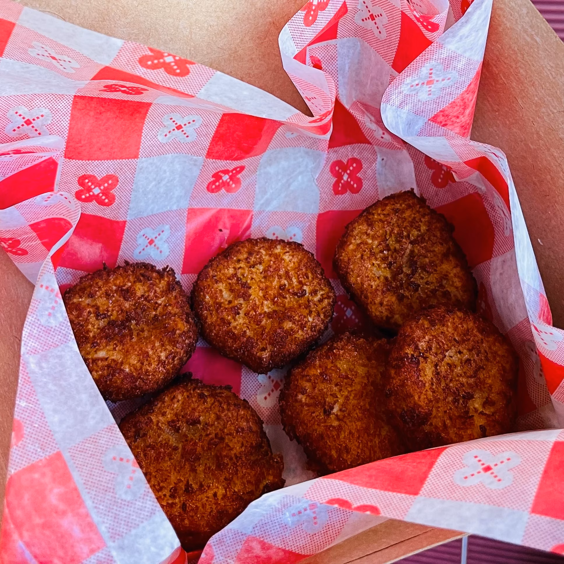 Six golden-brown fried patties in a red checkered paper liner.