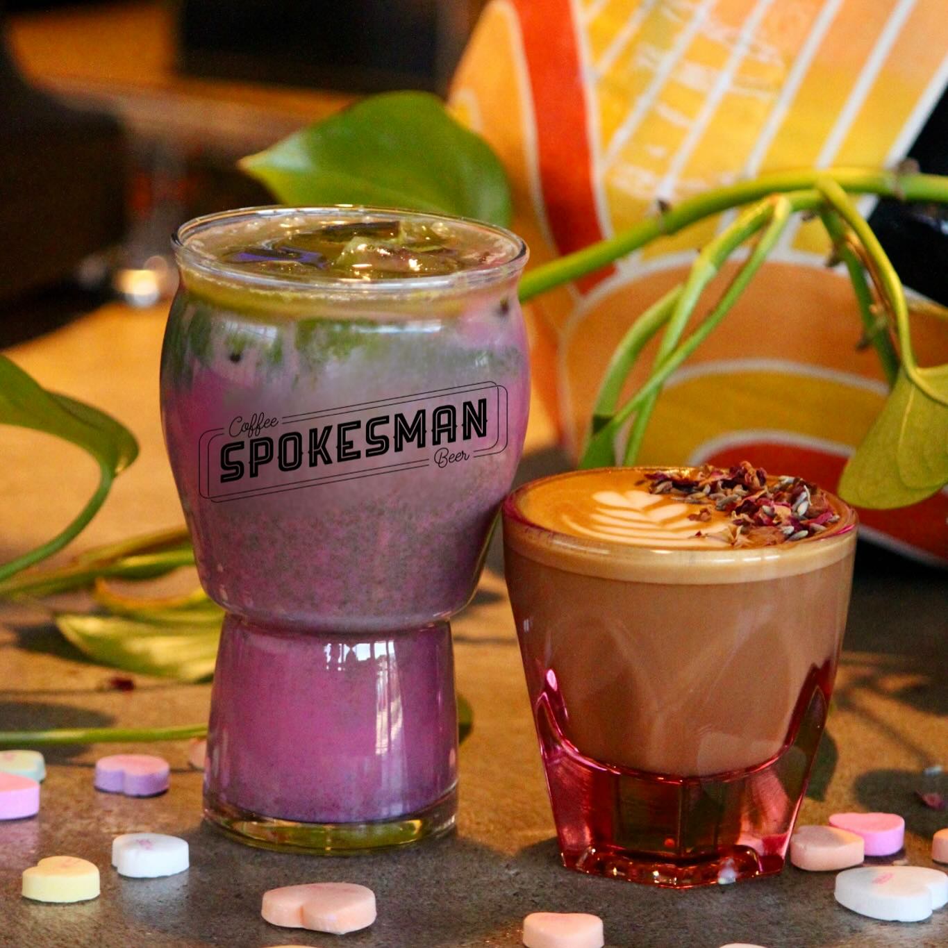 Pink layered drink, latte with foam, and conversation heart candies.
