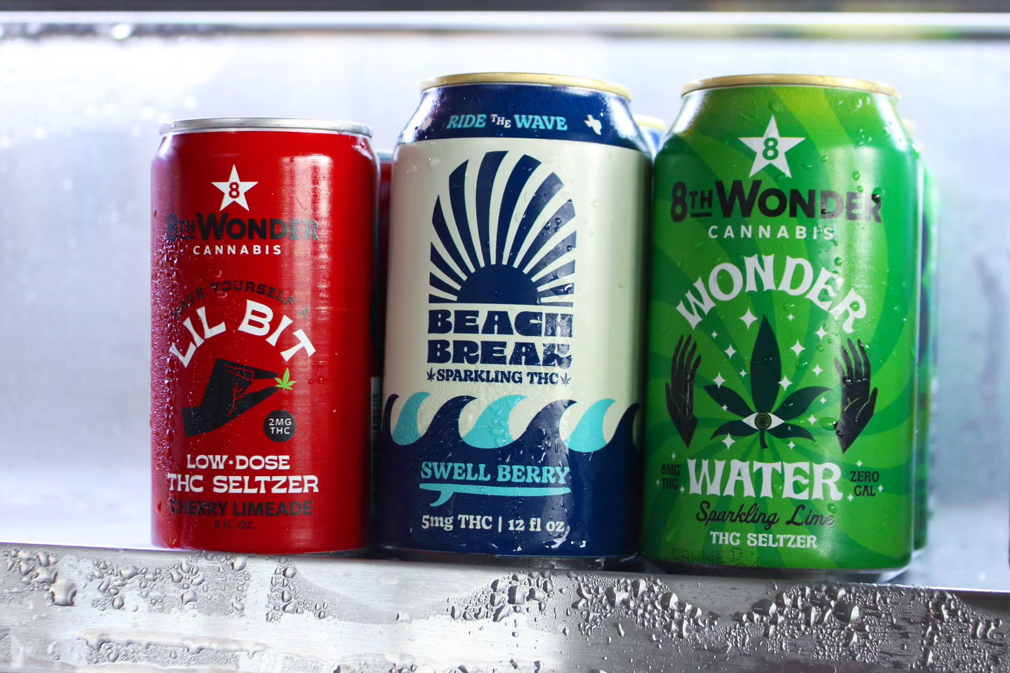 Three cold cans of THC seltzer with condensation.