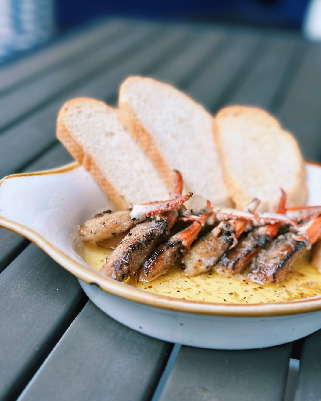 Cooked crab claws in seasoned oil with slices of bread.