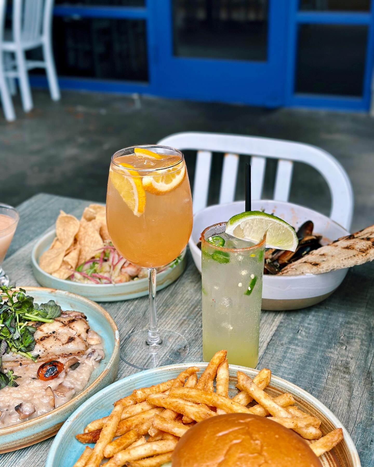 Various dishes including fries, seafood, and two drinks on a table.
