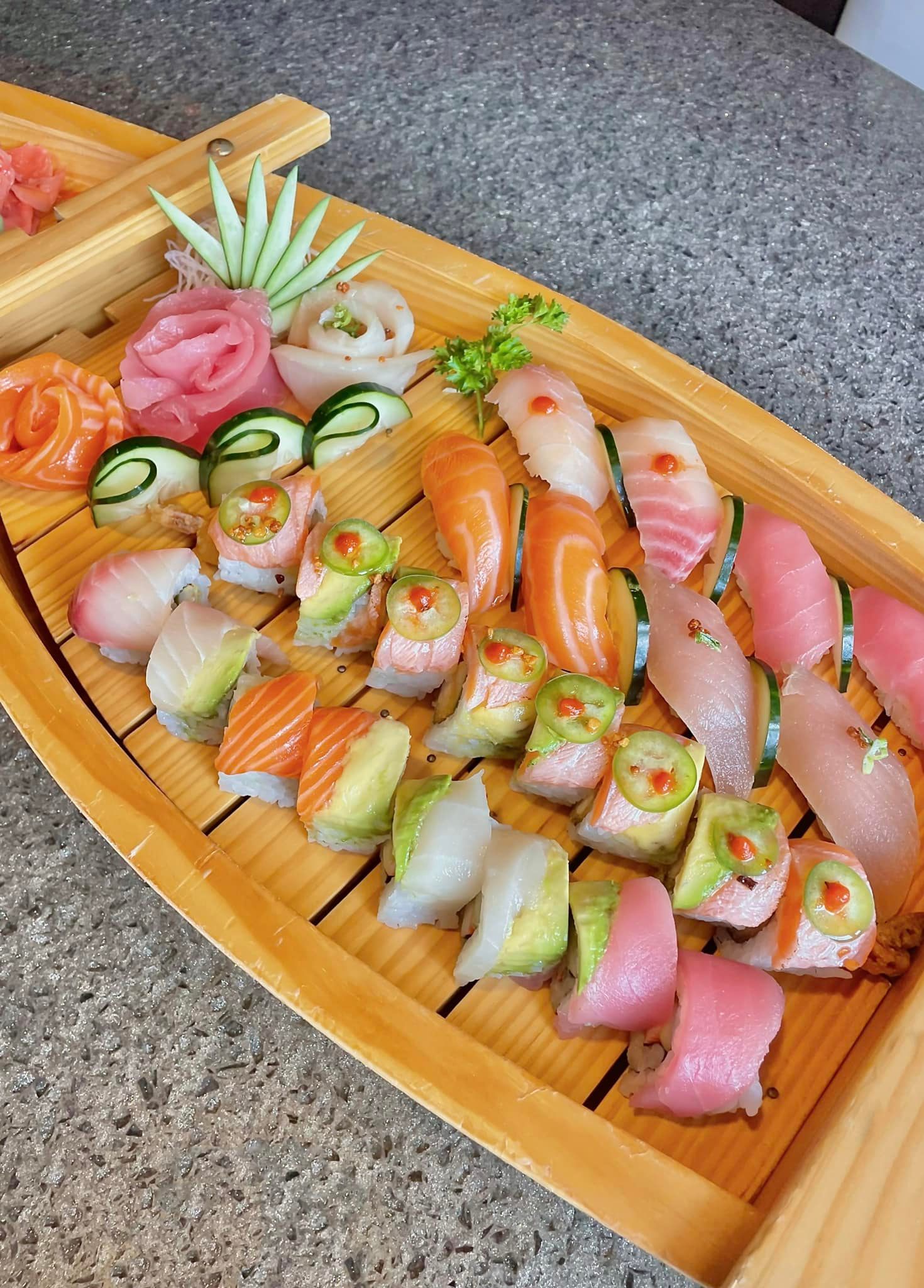 Sushi, sashimi, and rolls served in a large wooden boat.