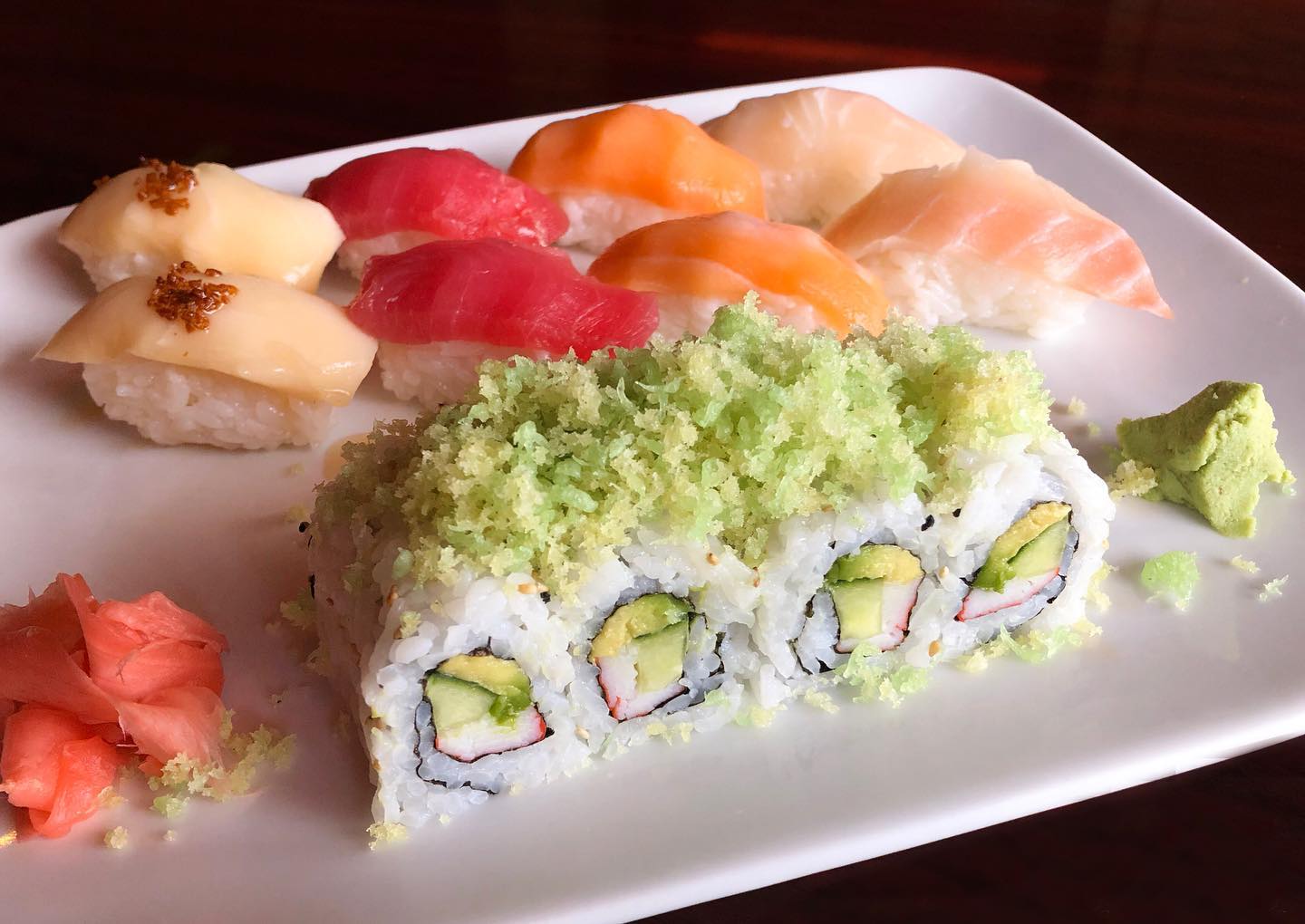 Assorted sushi plate with nigiri, a maki roll, wasabi, and ginger.
