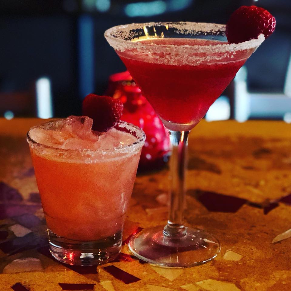 Two red drinks with sugared rims, one frozen, and strawberry garnishes.