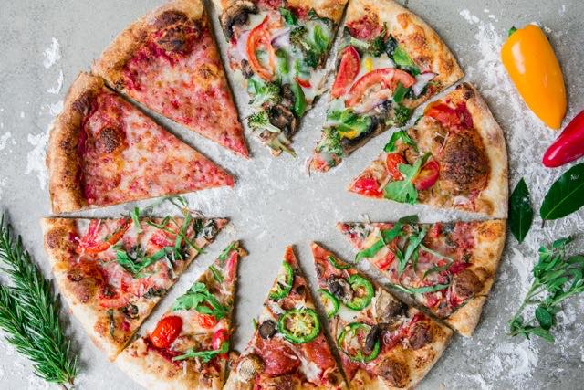 Pizza slices with cheese, vegetables, and meat toppings forming a circle.