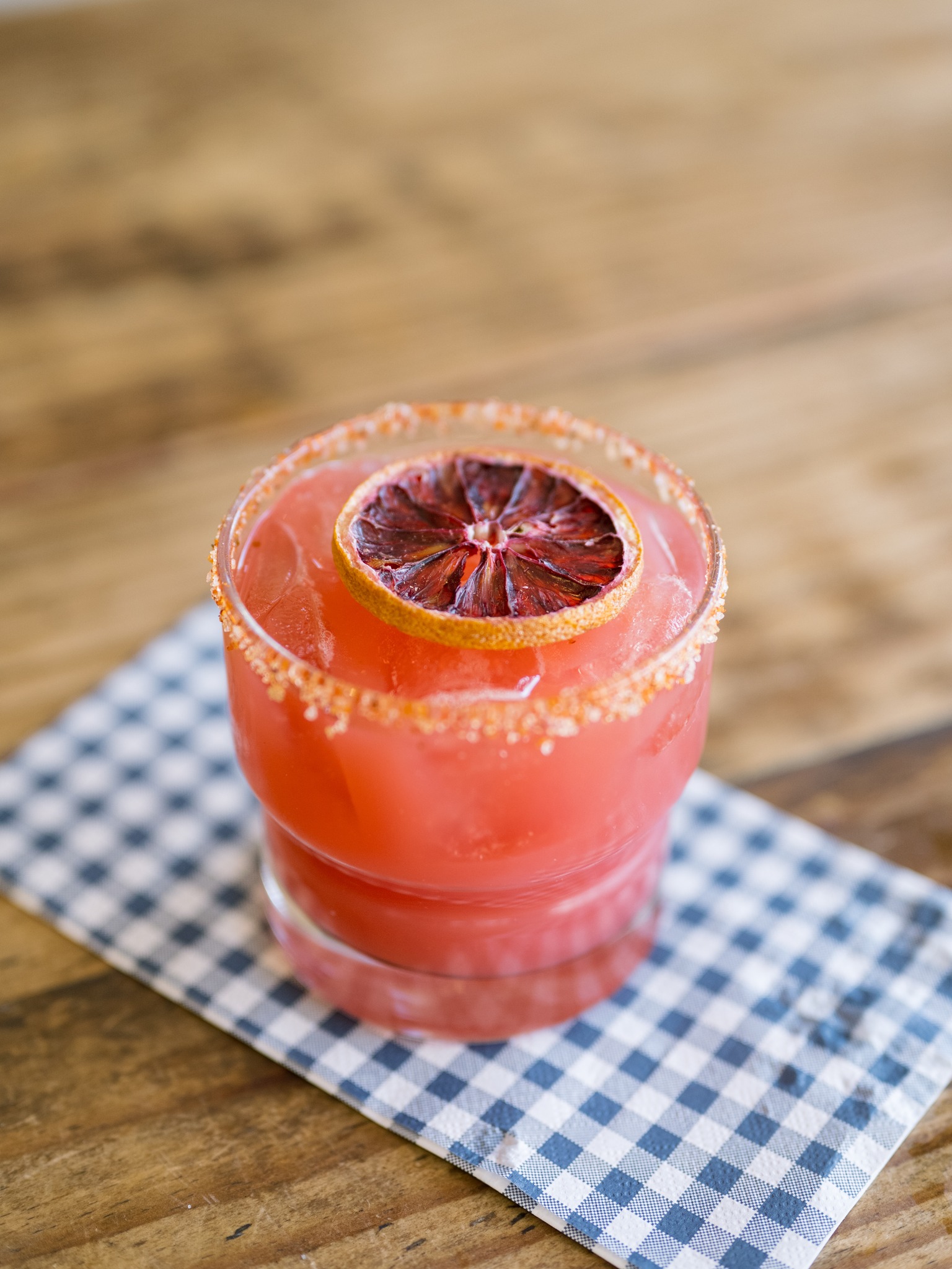 Pink drink with dried blood orange slice and garnished rim.