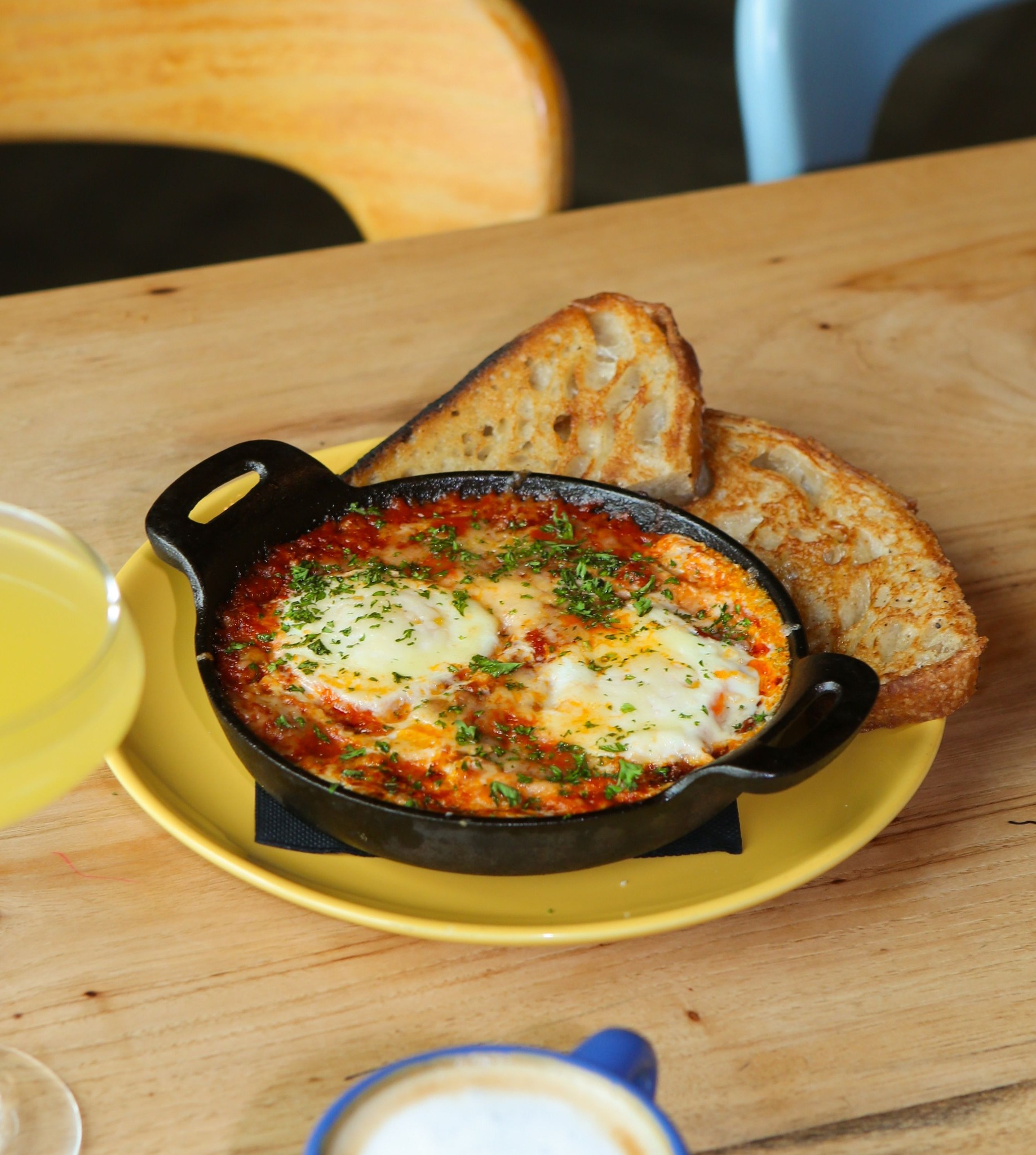 Skillet of baked eggs with tomato sauce, cheese, and toast.