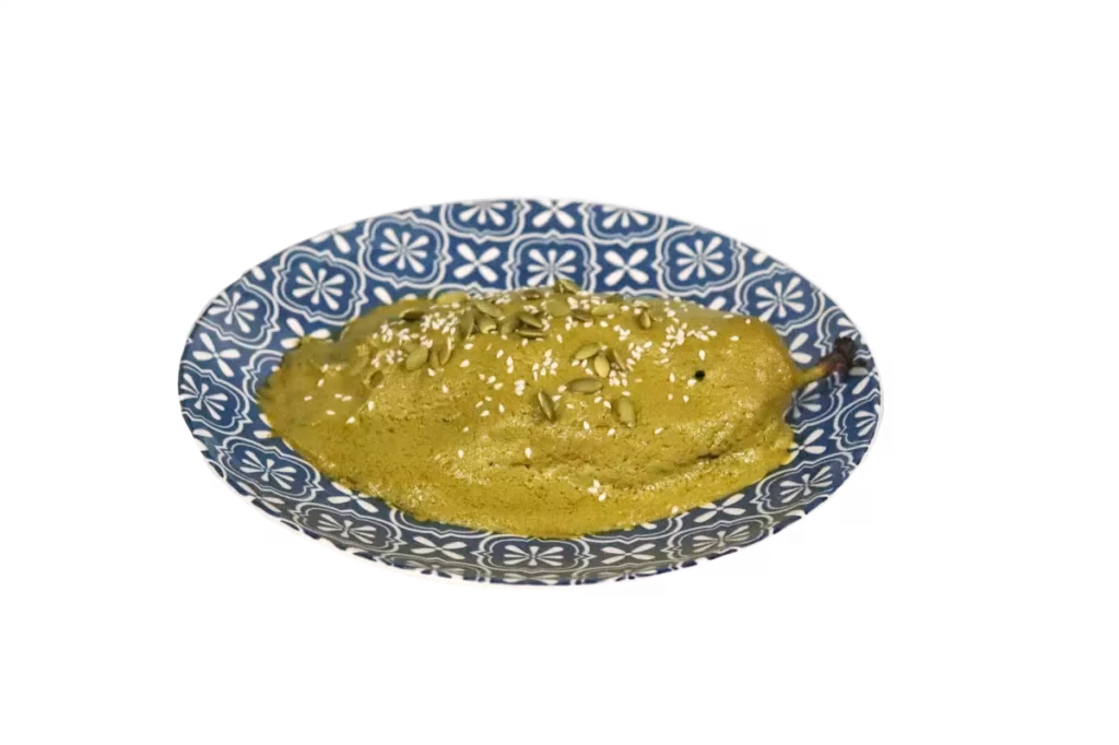 Green, oblong food with sauce and seeds on a blue and white plate.