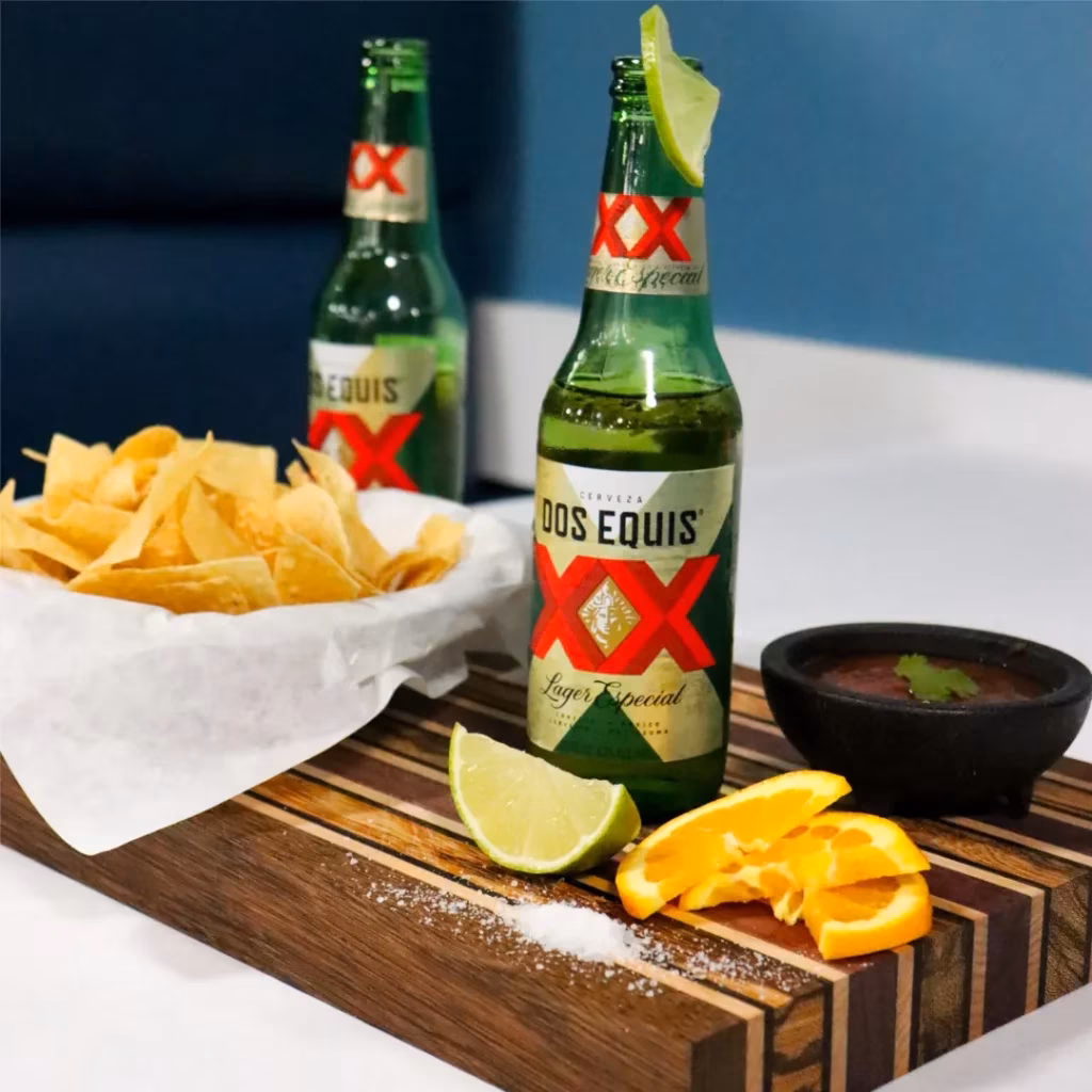 Dos Equis beer, tortilla chips, salsa, lime, and oranges.