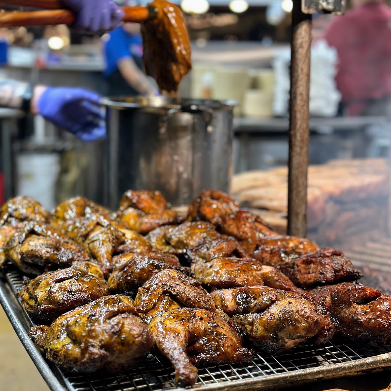 Many glazed chicken halves on a wire rack in a kitchen.