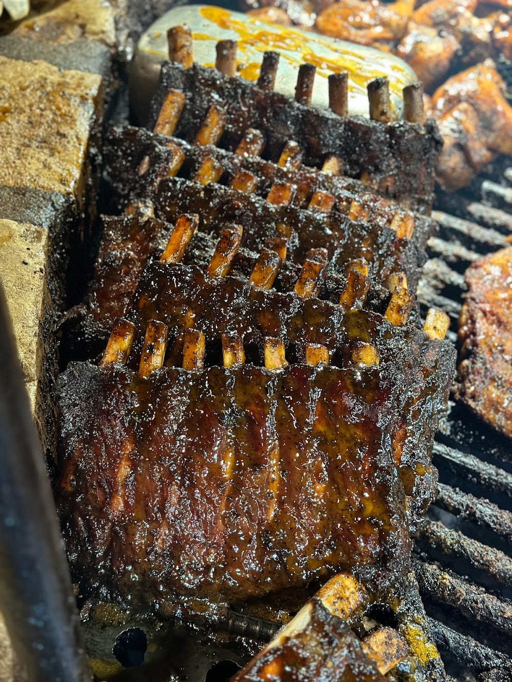 Multiple racks of dark, glazed ribs on a BBQ grill.