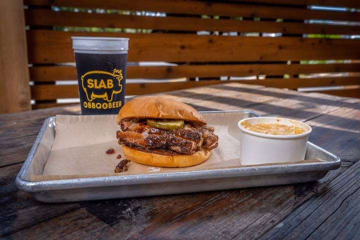 Brisket sandwich, creamy side dish, and branded drink on a tray.