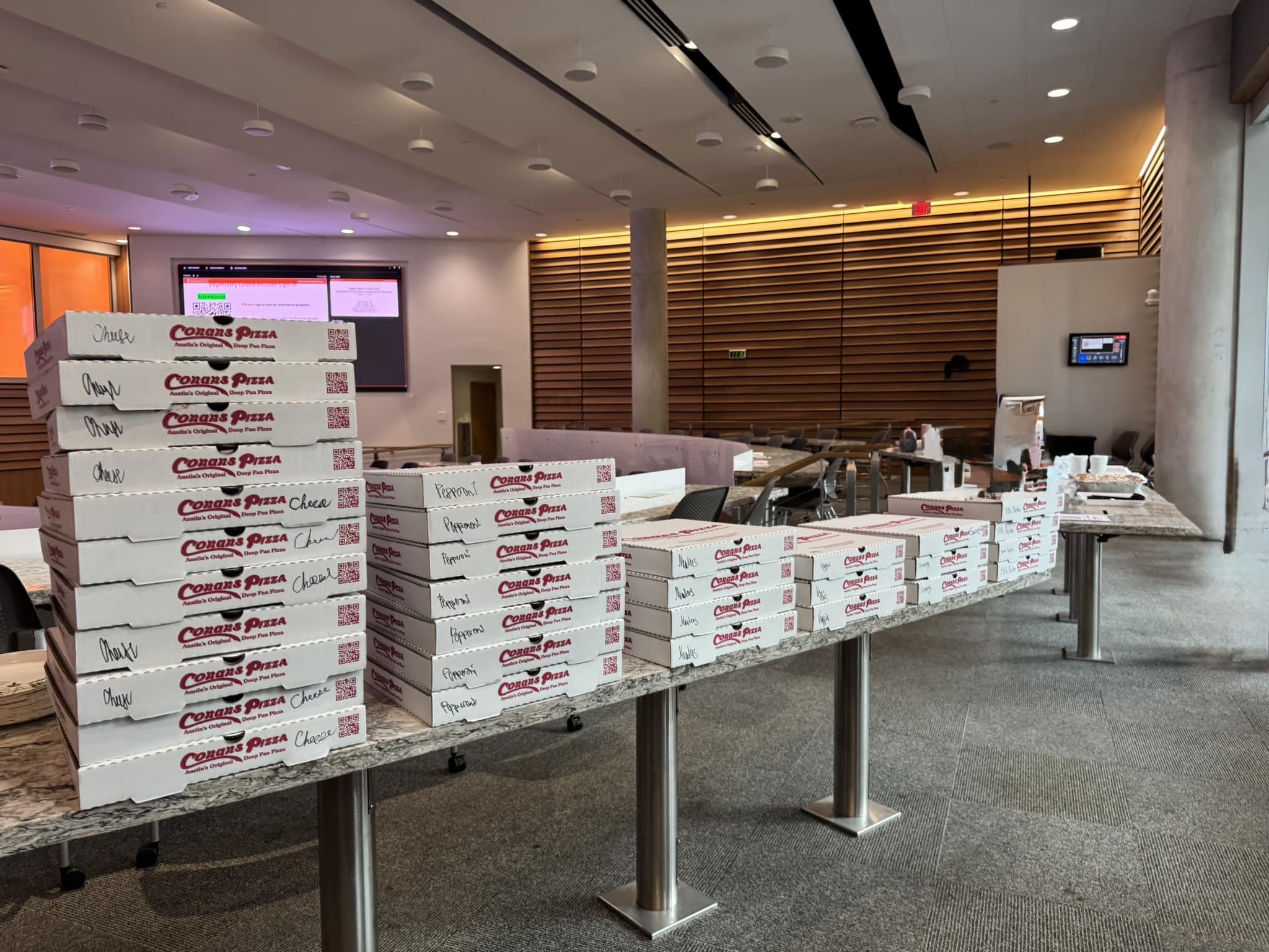 Stacks of Conans Pizza boxes on long tables indoors.