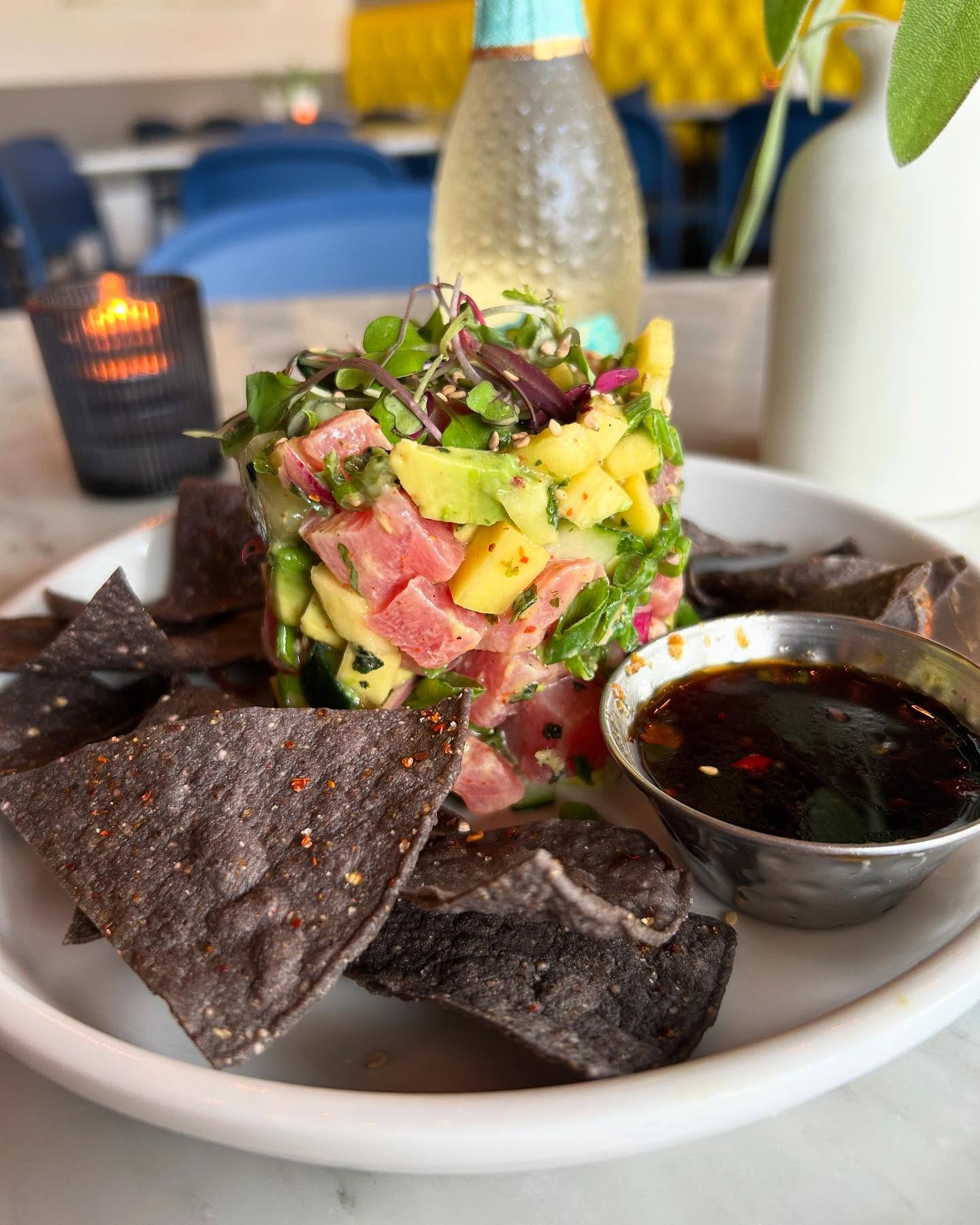 Tuna poke tower with avocado, mango, blue corn chips, and sauce.