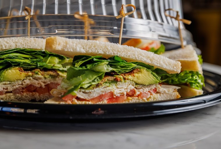 Club sandwiches layered with lettuce, avocado, sliced meat, and tomato.