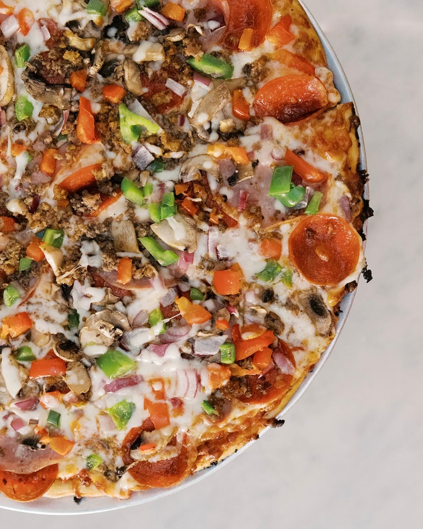 Pizza with pepperoni, ground meat, peppers, mushrooms, and onions.