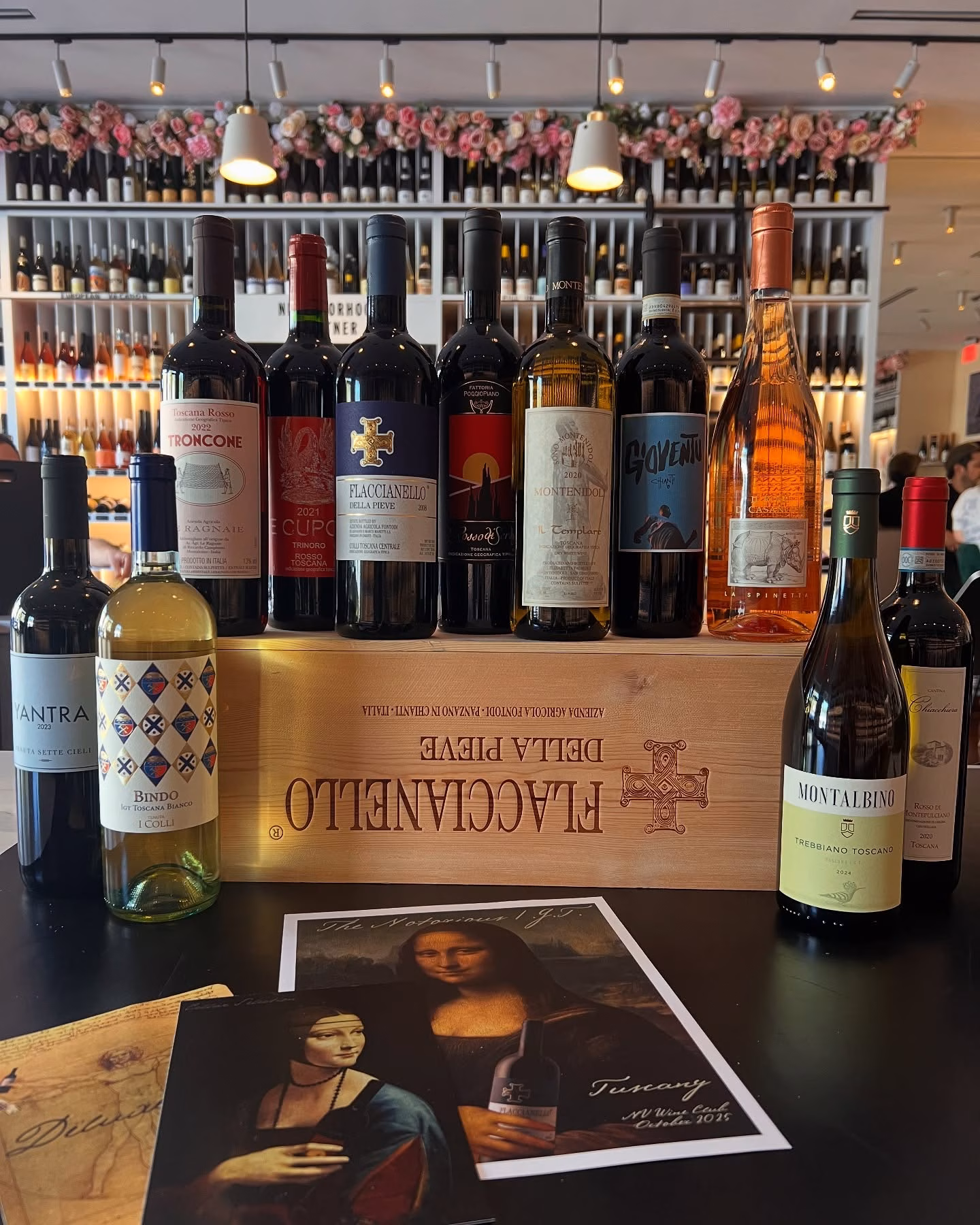 Twelve bottles of Italian wine displayed on a table and crate.