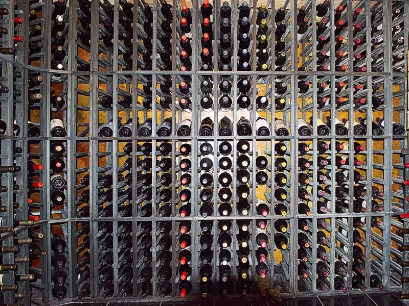 Wine cellar with rows of bottles stored in metal racks.