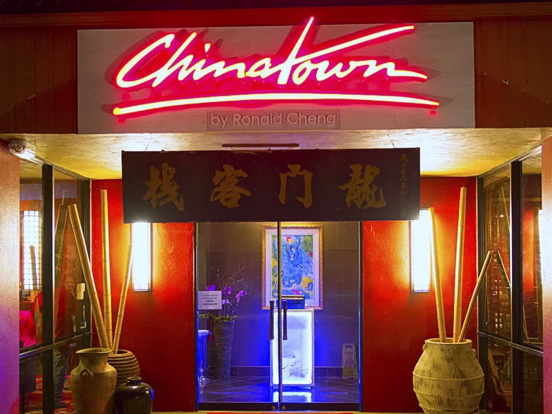 Entrance with glowing red 'Chinatown' sign, Chinese script, and bamboo.