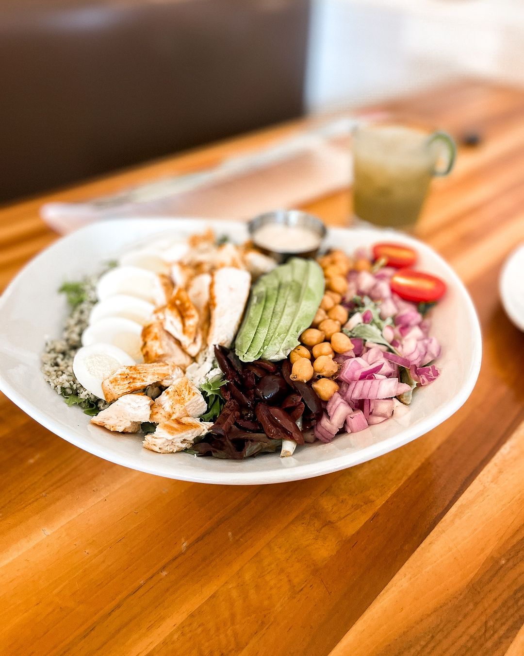 Salad with chicken, eggs, avocado, chickpeas, red onion, and tomatoes.
