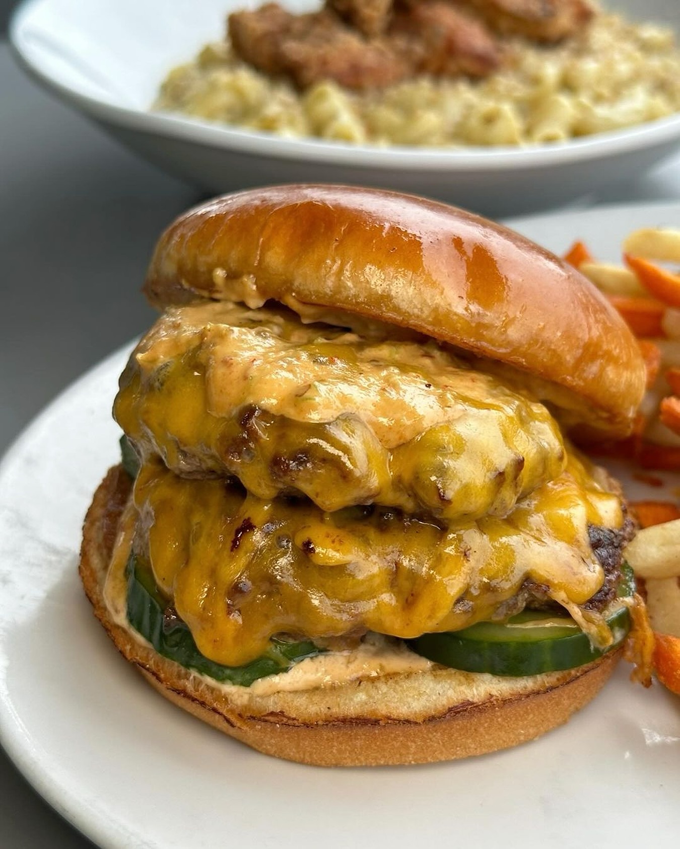 Double cheeseburger with melted cheese, pickles, and a side of fries.
