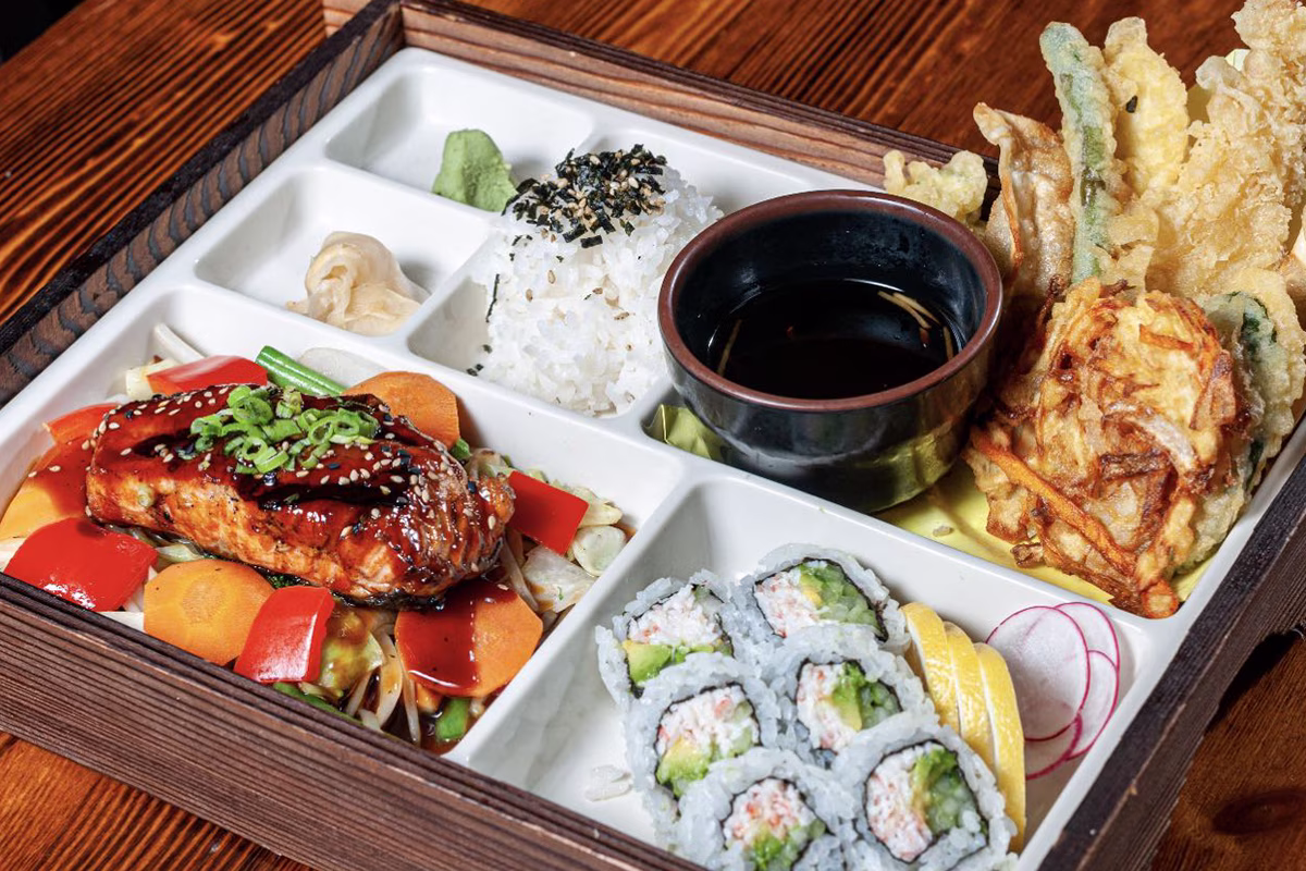 Japanese bento box with salmon, sushi, tempura, rice, and assorted sides.