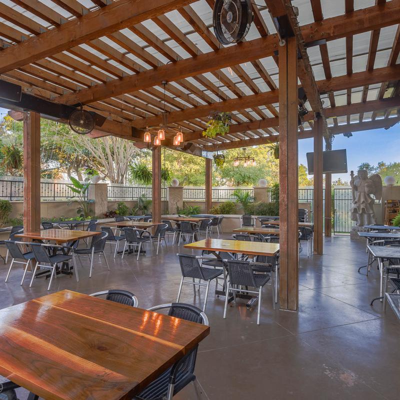 Spacious outdoor restaurant patio under a wooden pergola roof.
