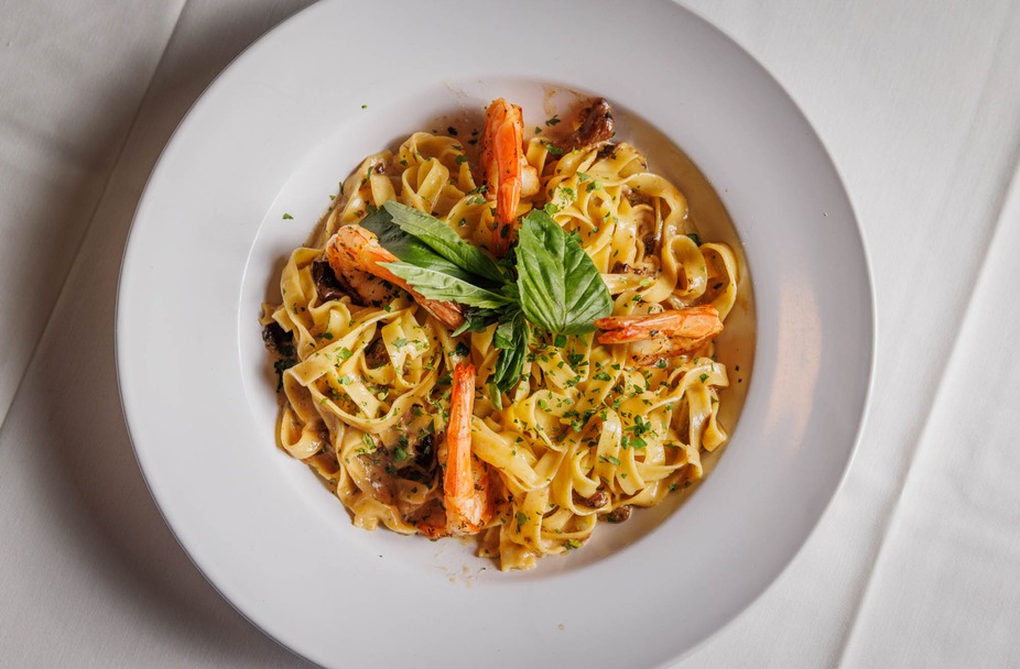 Plate of pasta with shrimp, fresh basil, and parsley.
