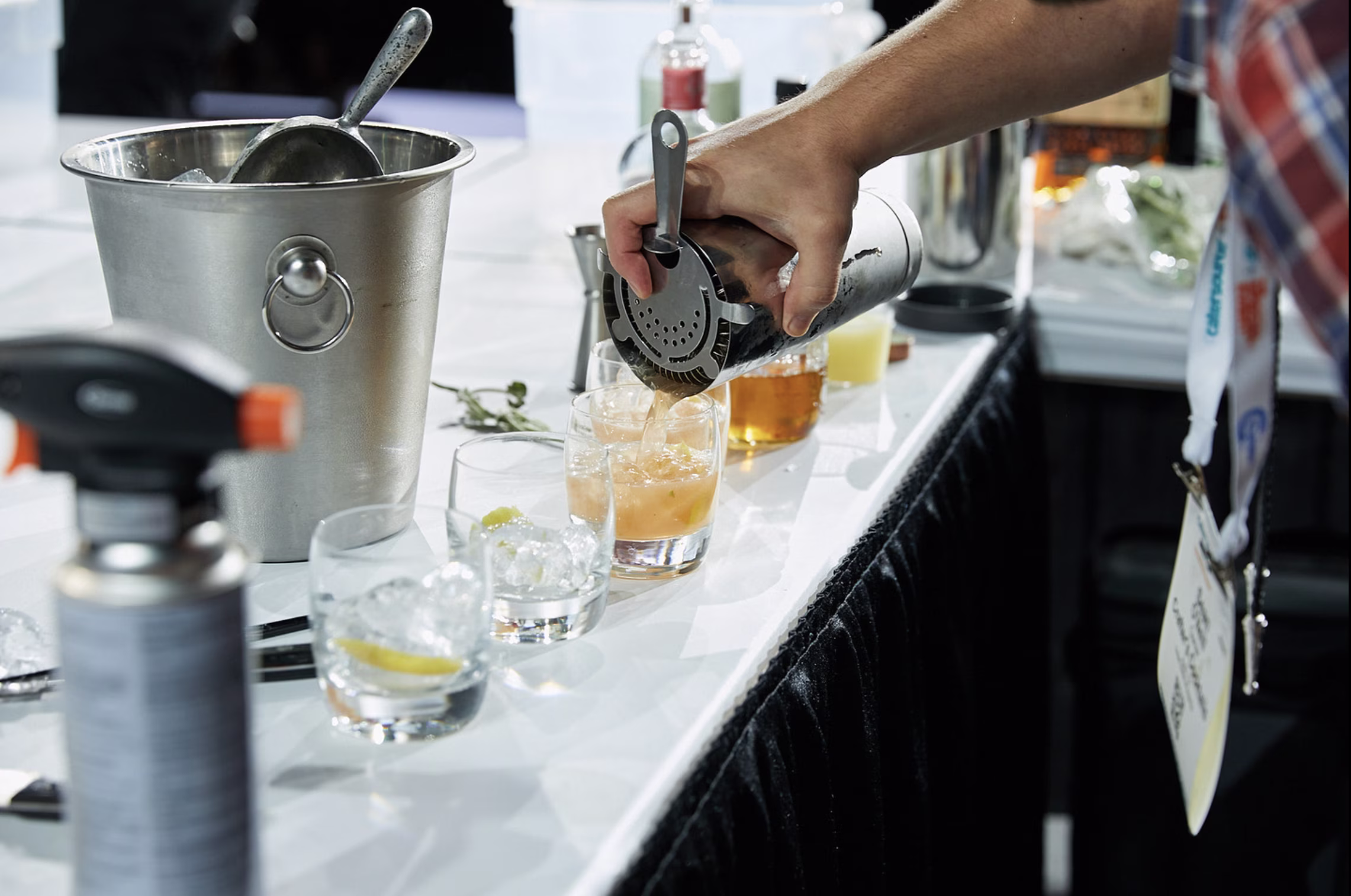 Person pouring a drink from shaker into glasses.