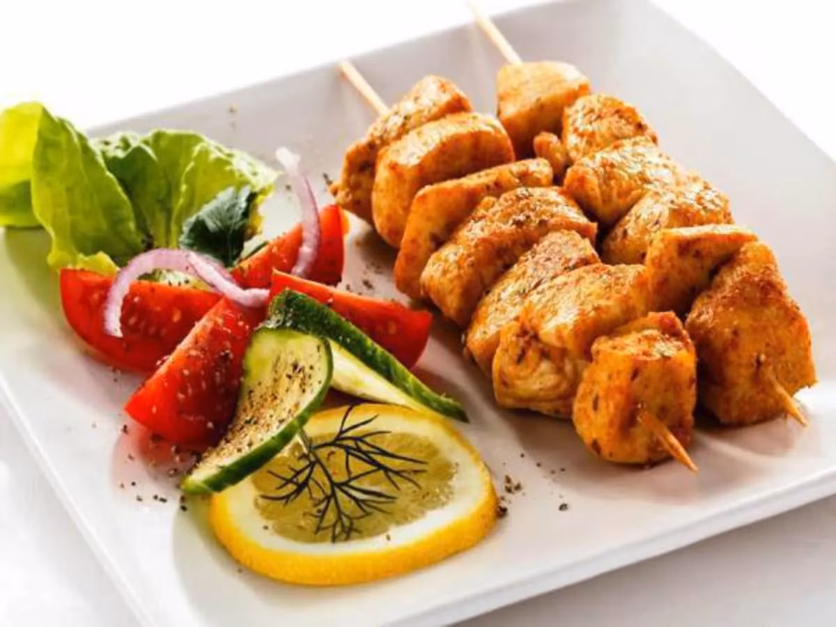 Cooked chicken skewers with a fresh side salad and lemon.