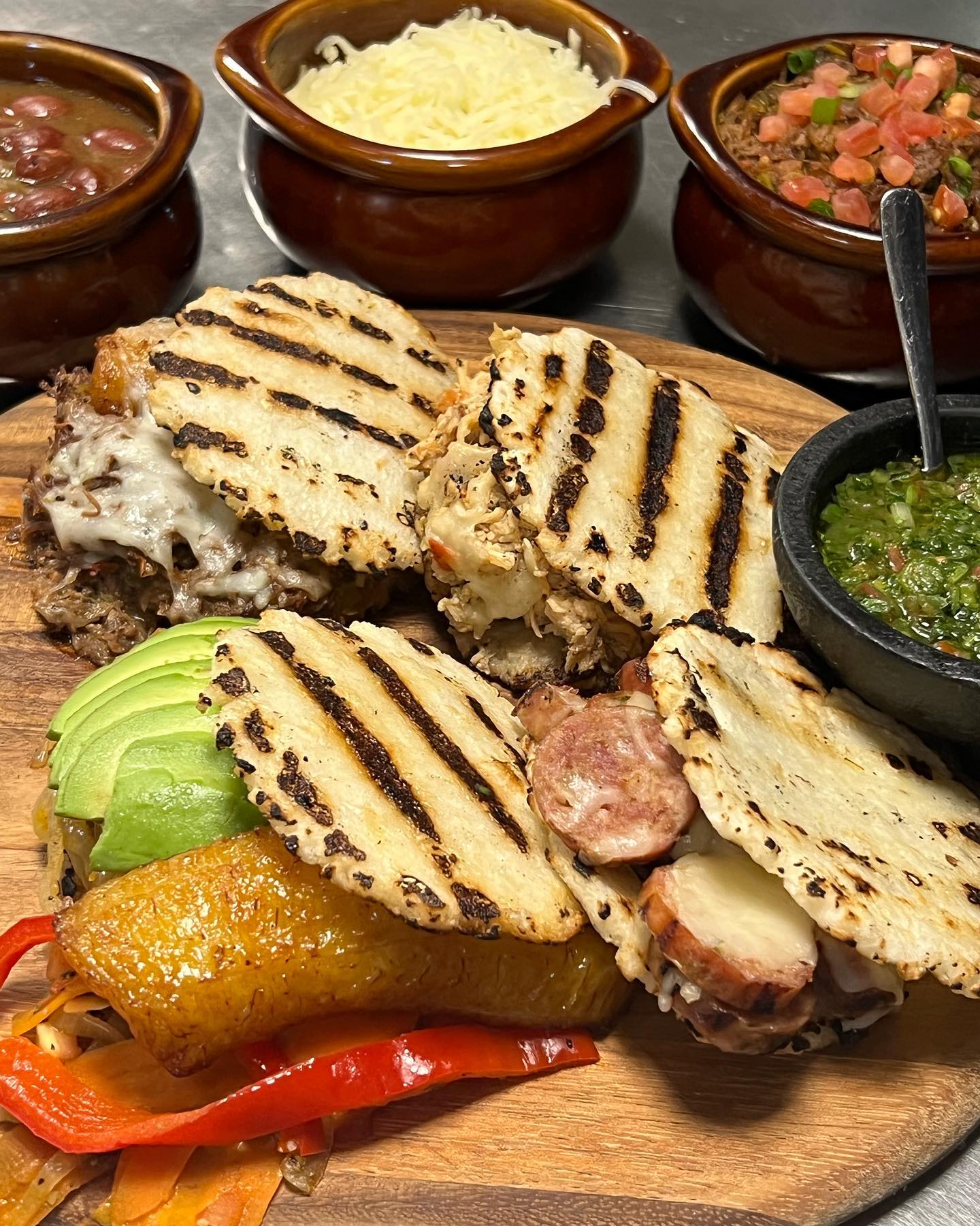 Grilled arepas with various fillings and small bowls of side dishes.