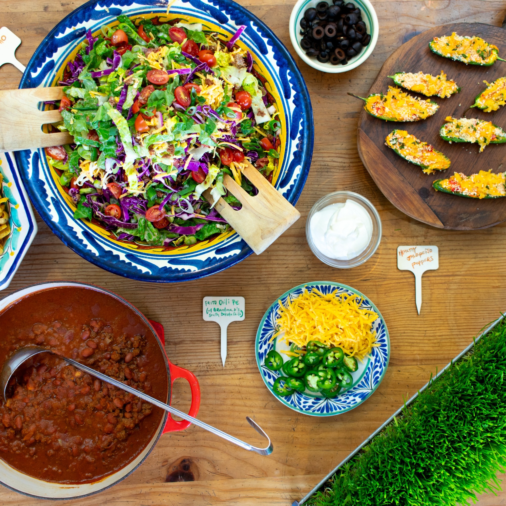 Table spread with chili, taco salad, jalapeño poppers, and various toppings.