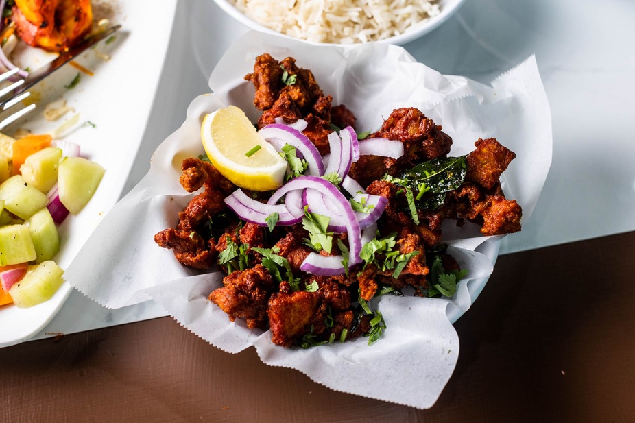 Fried chicken pieces with red onion, lemon, and fresh herbs.